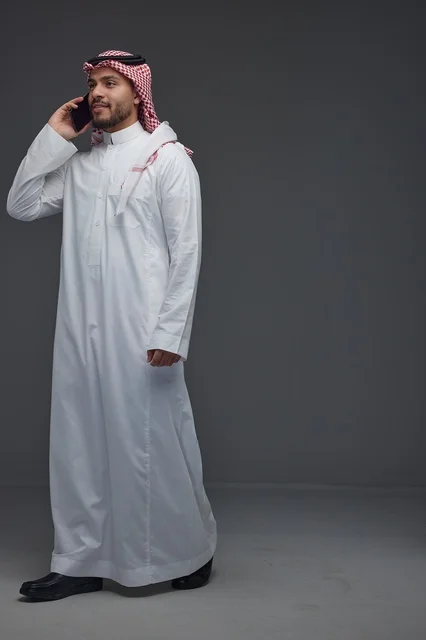Saudi Man in Traditional Dress Using Smartphone Studio