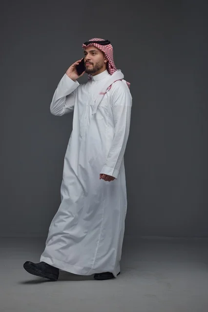 Saudi Man in Traditional Thobe Talking on Smartphone
