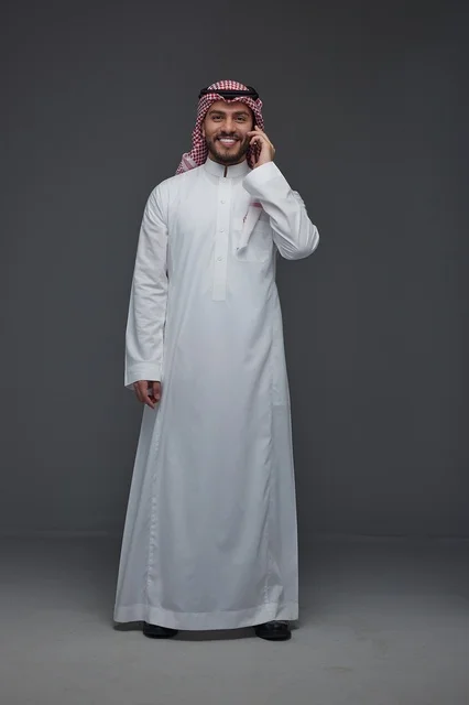 رجل سعودي بالزي التقليدي يستخدم الهاتف الذكي