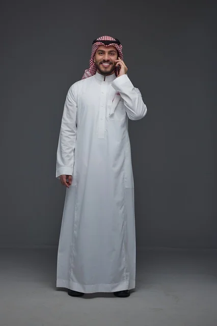 Saudi Man in Traditional Thobe Using Smartphone