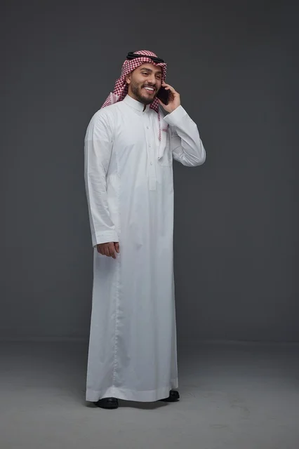 رجل سعودي بالزي التقليدي يتحدث عبر الهاتف الذكي
