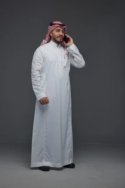 Saudi Man in Traditional Dress Using Smartphone in Studio