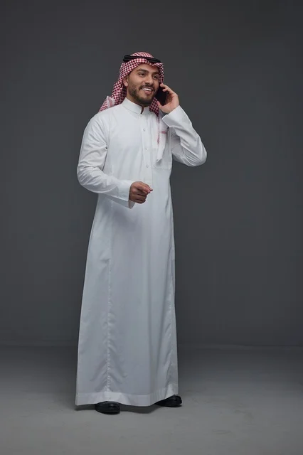 Saudi Man in Traditional Thobe Talking on Smartphone