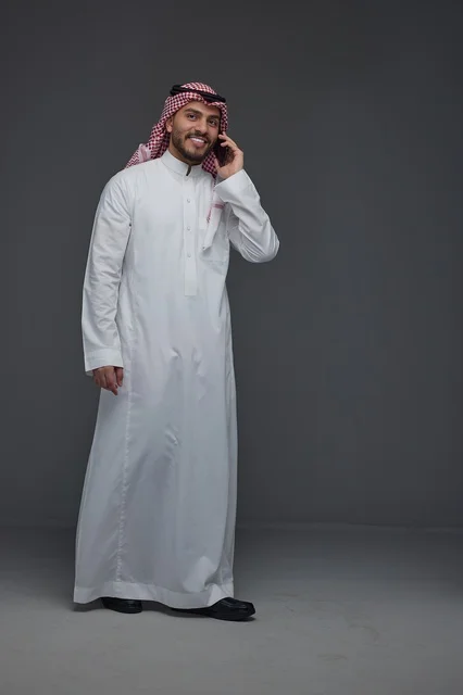 Saudi Man in Traditional Thobe Talking on Smartphone