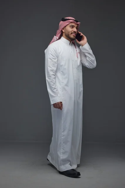 رجل سعودي بالزي التقليدي يتحدث عبر الهاتف الذكي