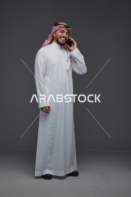 رجل سعودي بالزي التقليدي يتحدث عبر الهاتف الذكي