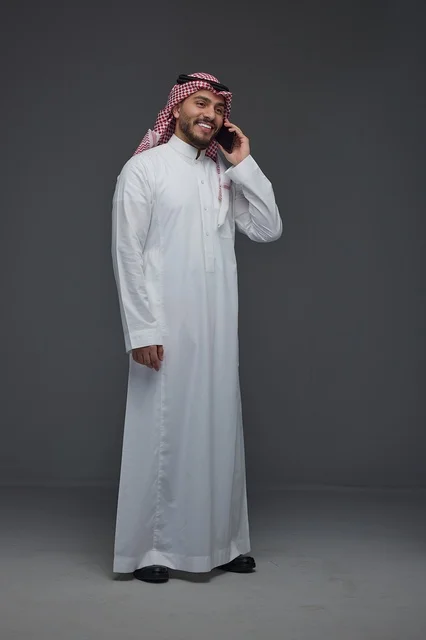 رجل سعودي بالزي التقليدي يتحدث عبر الهاتف الذكي
