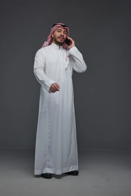 رجل سعودي بالزي التقليدي يتحدث عبر الهاتف الذكي