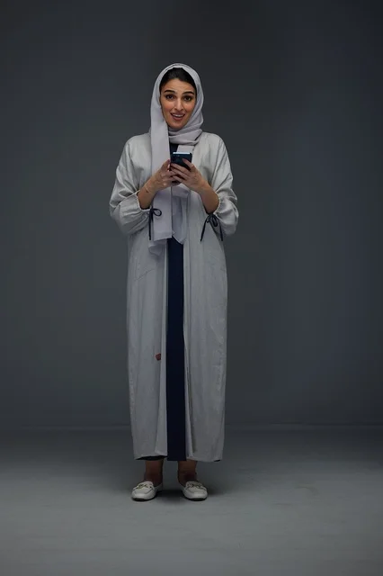 Saudi Woman Using Smartphone on Grey Studio Background