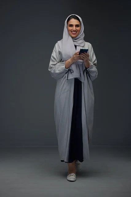 Saudi Woman Using Smartphone in Grey Studio Setting