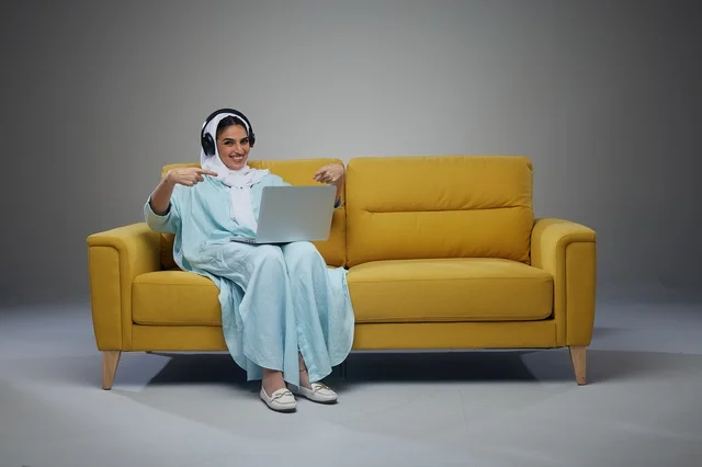 Saudi Woman with Laptop on Yellow Sofa