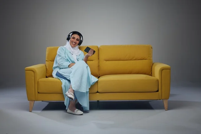 Saudi Woman with Headphones on Yellow Sofa in Studio