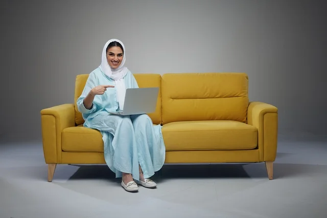 Saudi Woman with Laptop on Yellow Sofa in Studio