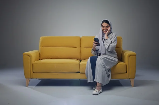 Saudi Woman on Yellow Sofa Using Smartphone