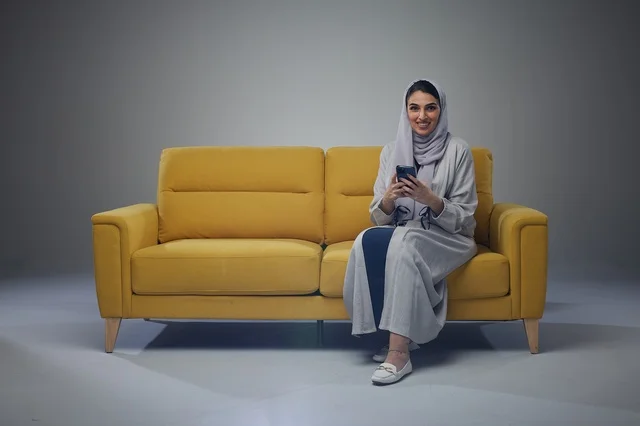 Saudi Woman on Yellow Sofa Using Smartphone