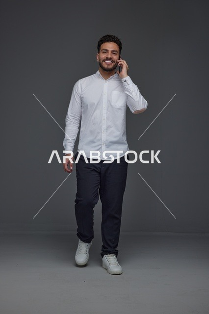رجل سعودي يتحدث بالهاتف الذكي ويمشي في الاستوديو