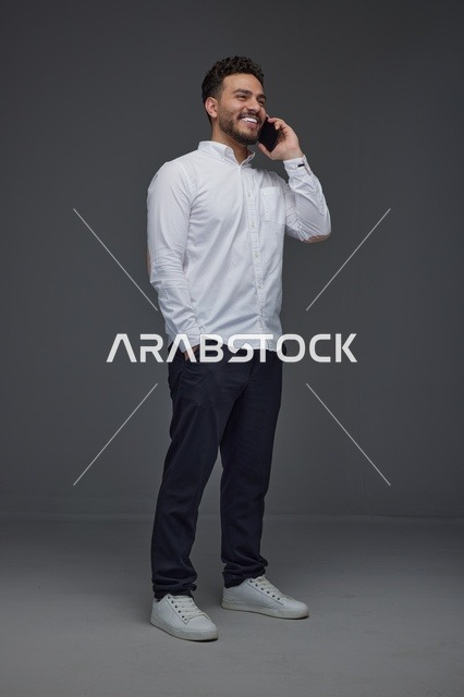 رجل سعودي مبتسم يتحدث عبر الهاتف الذكي في الاستوديو
