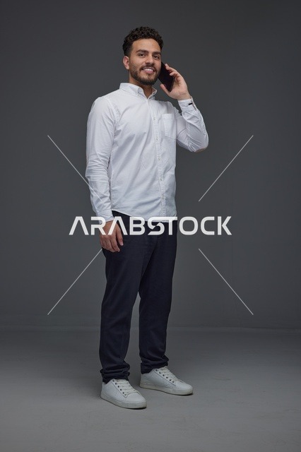 رجل سعودي يتحدث عبر الهاتف الذكي في الاستوديو