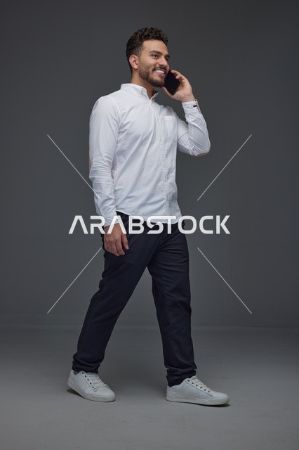 رجل سعودي يمشي ويتحدث بالهاتف الذكي في الاستوديو