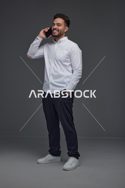 رجل سعودي مبتسم يتحدث عبر الهاتف المحمول في الاستوديو