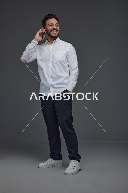 رجل سعودي يتحدث عبر الهاتف في استوديو رمادي