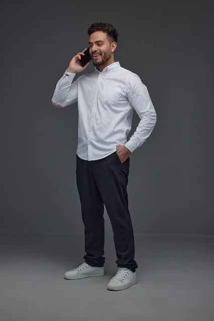 Saudi Man Talking on Smartphone in Studio Grey Background
