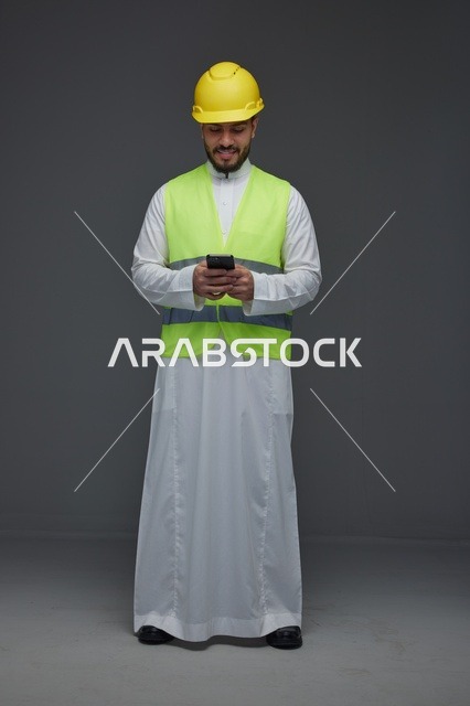 مهندس سعودي بمعدات السلامة يستخدم الهاتف الذكي