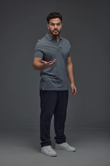 Saudi Man Gesturing in Grey Polo Shirt Studio Background