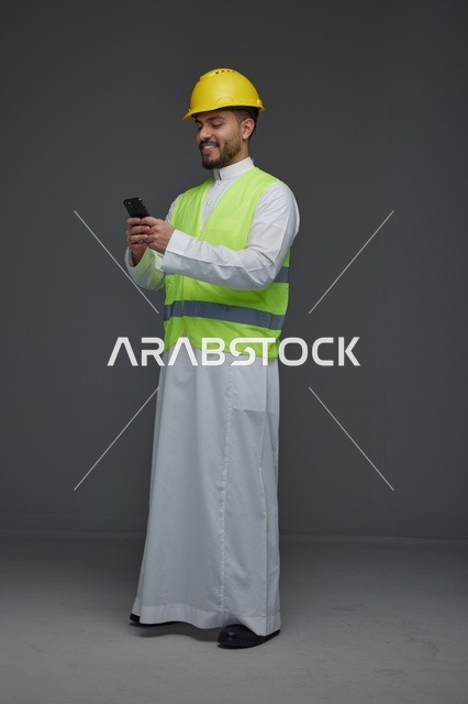 مهندس سعودي بمعدات السلامة يستخدم الهاتف الذكي