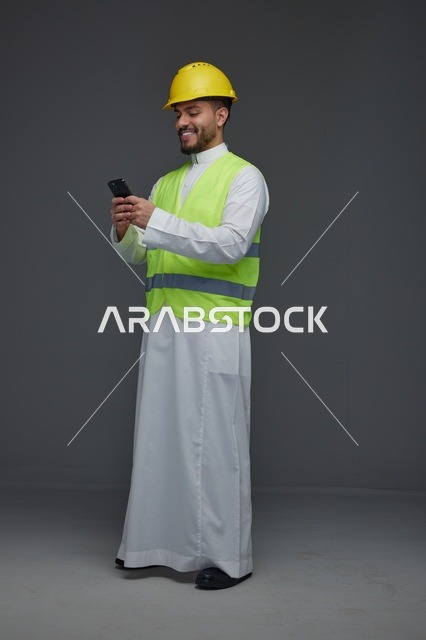 مهندس سعودي بمعدات السلامة يستخدم الهاتف الذكي
