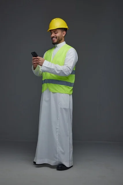 مهندس سعودي بمعدات السلامة يستخدم الهاتف الذكي