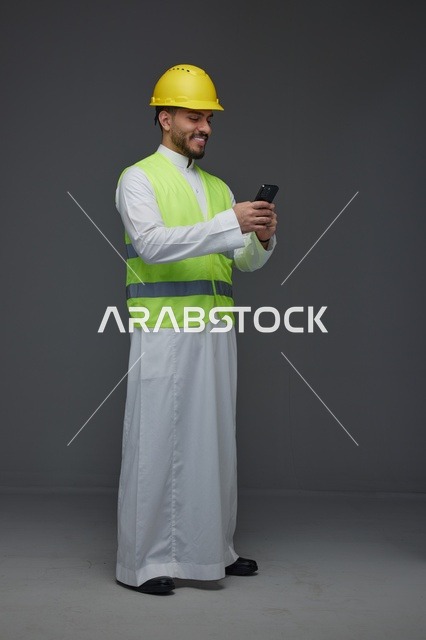 مهندس سعودي بمعدات السلامة يستخدم الهاتف الذكي