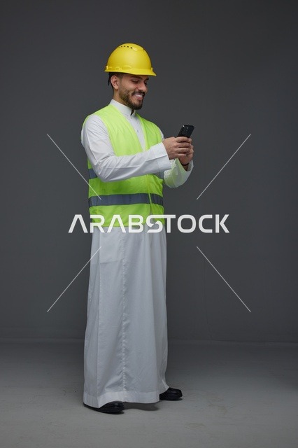 مهندس سعودي بمعدات السلامة يستخدم الهاتف الذكي