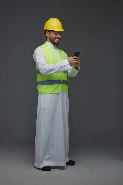 مهندس سعودي بمعدات السلامة يستخدم الهاتف الذكي