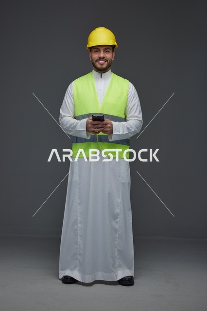 مهندس سعودي بمعدات السلامة يستخدم الهاتف الذكي