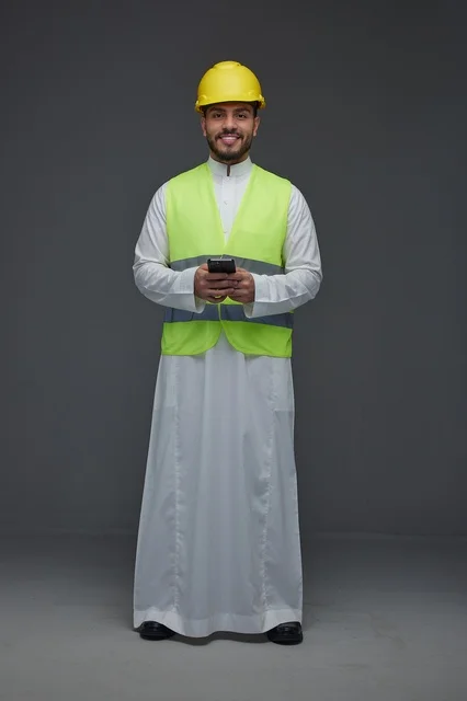 مهندس سعودي بمعدات السلامة يستخدم الهاتف الذكي
