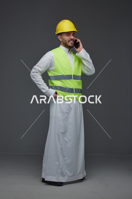 مهندس سعودي بسترة أمان يتحدث بالهاتف المحمول في استوديو