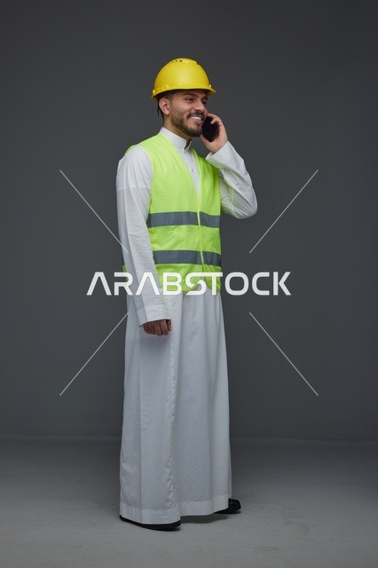 مهندس سعودي يرتدي سترة أمان يتحدث عبر الهاتف
