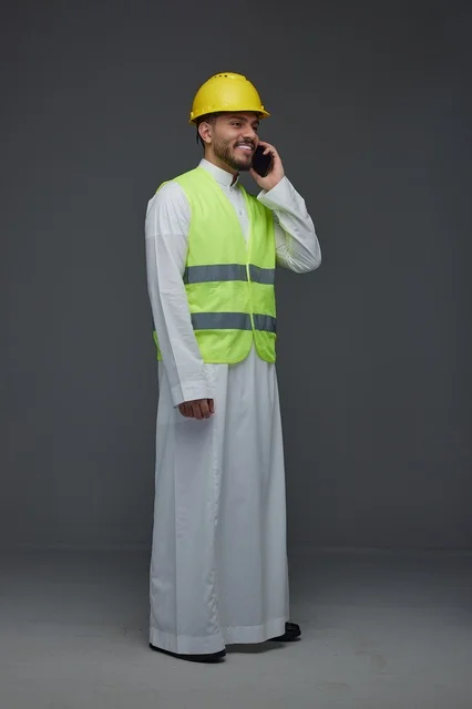 مهندس سعودي يرتدي سترة أمان يتحدث عبر الهاتف