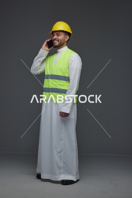 مهندس سعودي بمعدات السلامة يتحدث عبر الهاتف المحمول