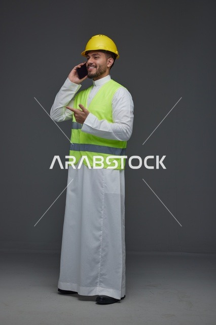 مهندس سعودي يرتدي سترة السلامة يتحدث عبر الهاتف