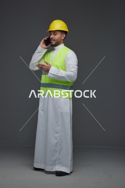 مهندس سعودي يرتدي سترة أمان ويتحدث عبر الهاتف