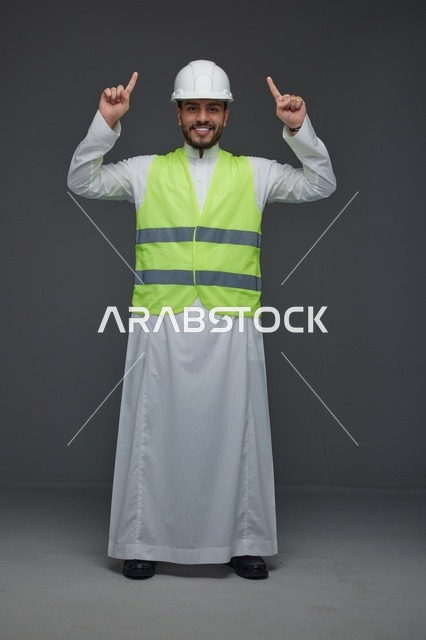مهندس سعودي يرتدي سترة السلامة ويشير للأعلى
