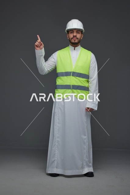 مهندس سعودي يرتدي سترة السلامة ويشير للأعلى