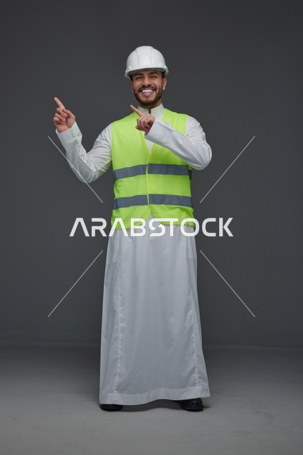 مهندس سعودي يرتدي سترة السلامة ويشير للجانب