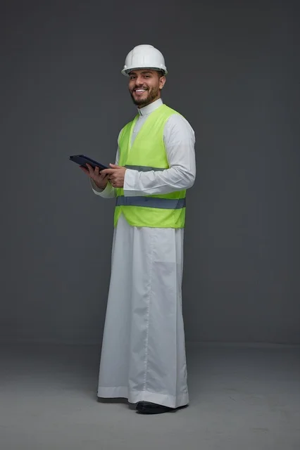 مهندس سعودي يحمل جهازاً لوحياً بملابس السلامة