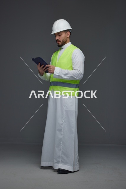 مهندس سعودي بملابس السلامة يستخدم جهاز لوحي