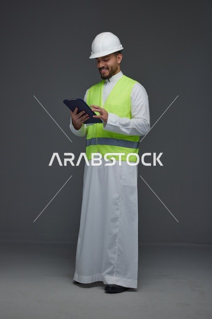 مهندس سعودي يرتدي سترة السلامة ويستخدم تابلت