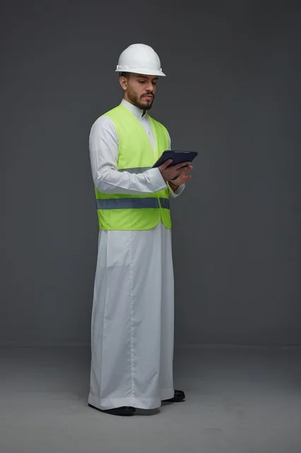 مهندس سعودي يرتدي سترة السلامة ويستخدم جهاز لوحي