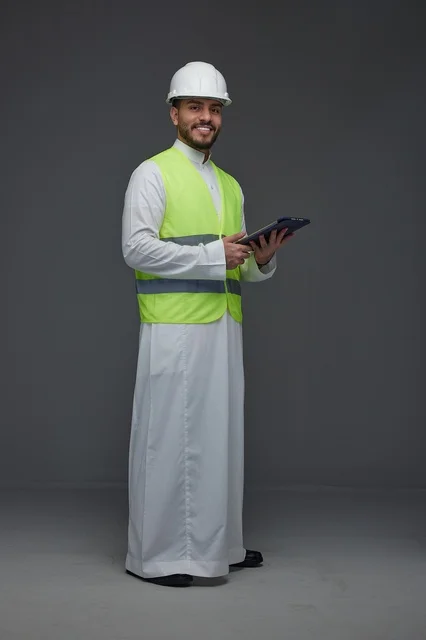 مهندس سعودي يرتدي سترة الأمان ويحمل جهازا لوحيا